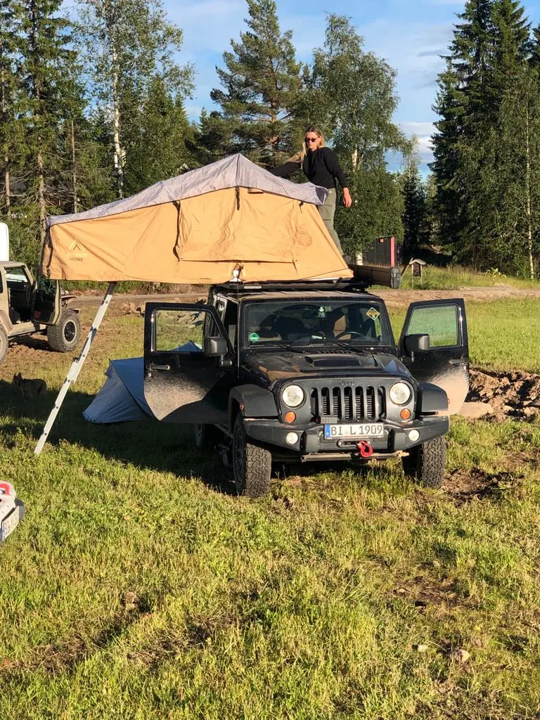 Jeep Wrangler mit aufgeklapptem Dachzelt auf einer Wiese
