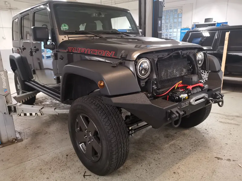 Jeep Wrangler Rubicon mit Seilwinde und roten Bergehaken in der Werkstatt