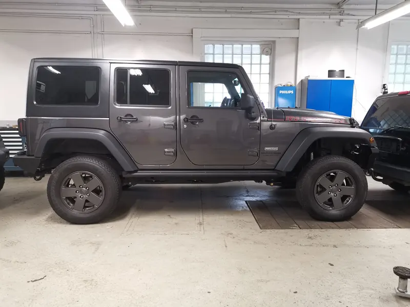 Grauer Jeep Wrangler Unlimited in der Seitenansicht in der Werkstatt