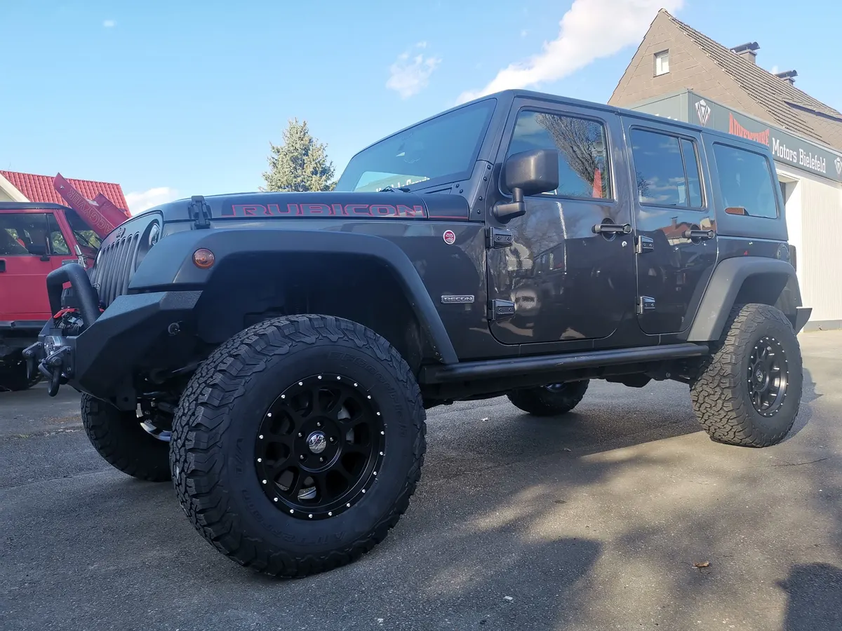 Umgebauter Jeep Wrangler Rubicon mit Offroad-Reifen vor dem Firmengebäude