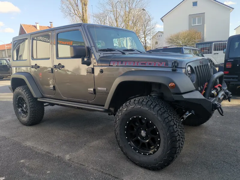 Höhergelegter Jeep Wrangler Rubicon mit Offroad-Reifen, schwarzen Felgen und Stoßfänger mit Seilwinde