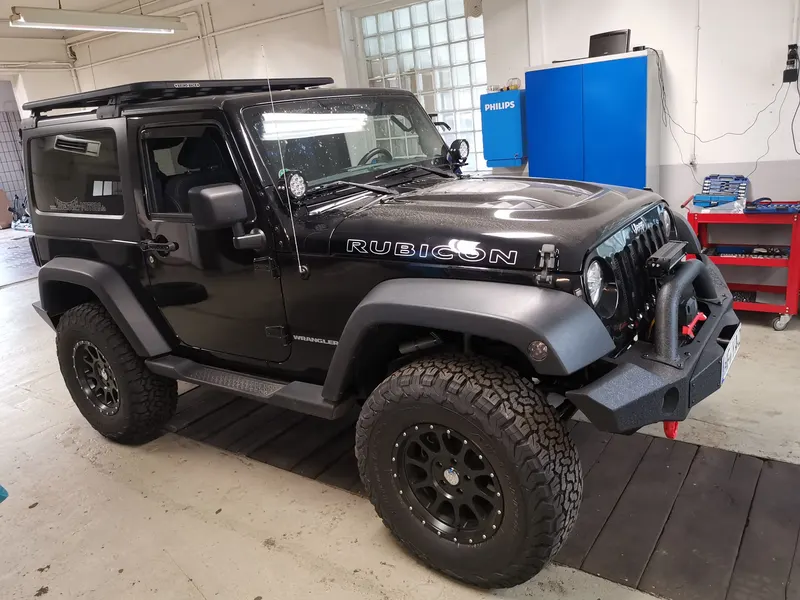 Schwarzer Jeep Wrangler Rubicon mit Dachträger und Stahlstoßstange in der Werkstatt