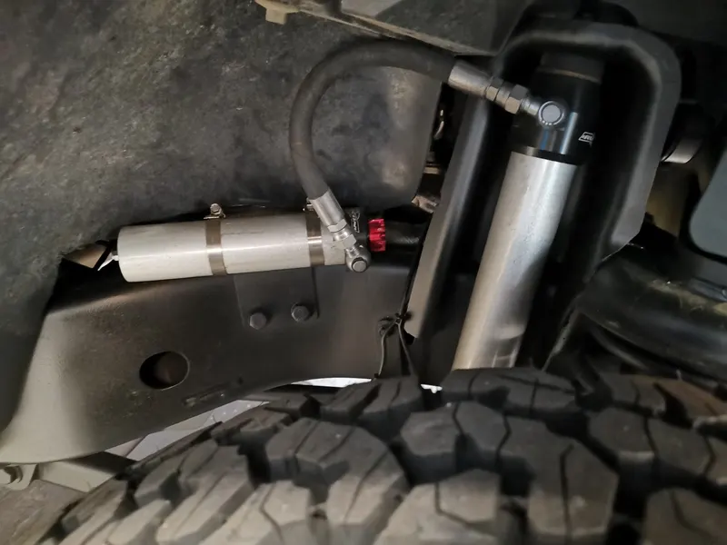 Stoßdämpfer mit Ausgleichsbehälter am Radlauf, darunter ein Offroad-Reifen