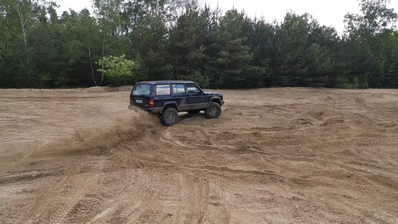 Jeep Cherokee driftet über eine Sandfläche
