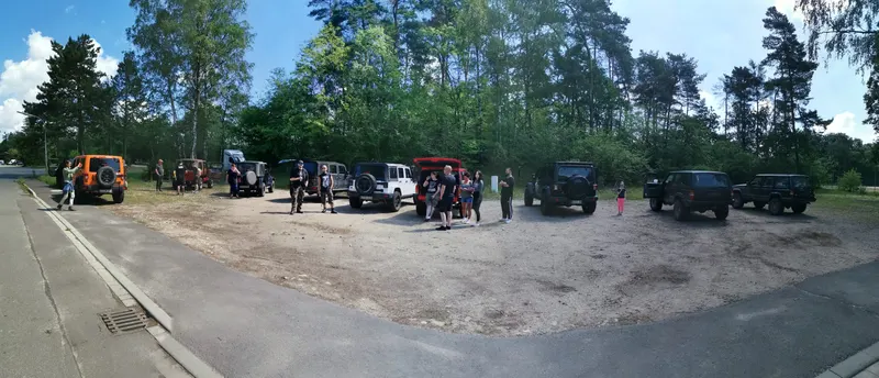 Viele Jeeps und Teilnehmer auf einem Parkplatz am Waldrand