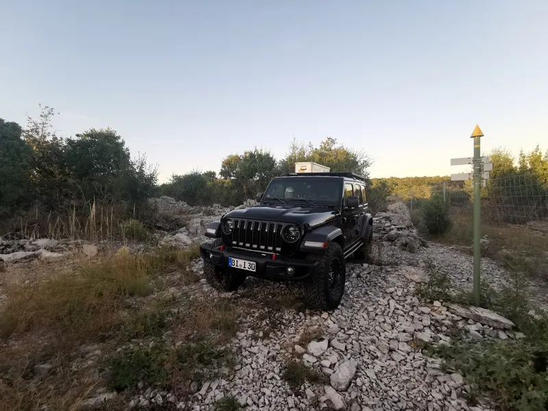 Schwarzer Jeep Wrangler auf felsigem Gelände in der Abendsonne