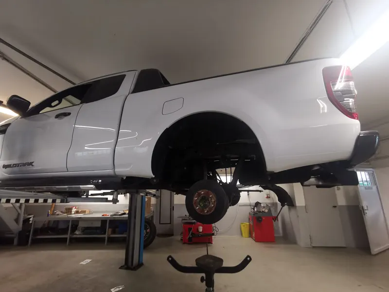 Weißer Pick-up auf der Hebebühne, Rad abgenommen