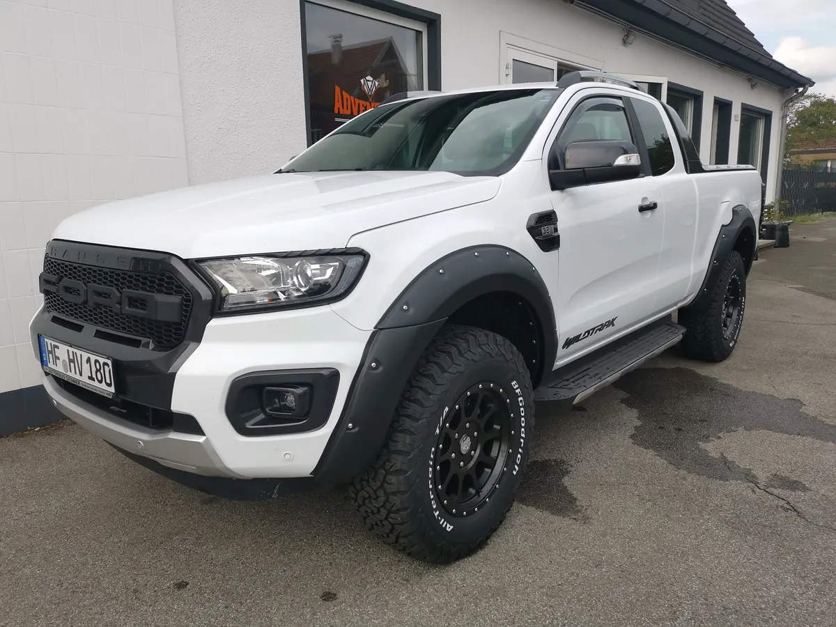 Weißer Ford Ranger mit Kotflügelverbreiterungen und Offroad-Rädern vor der Werkstatt