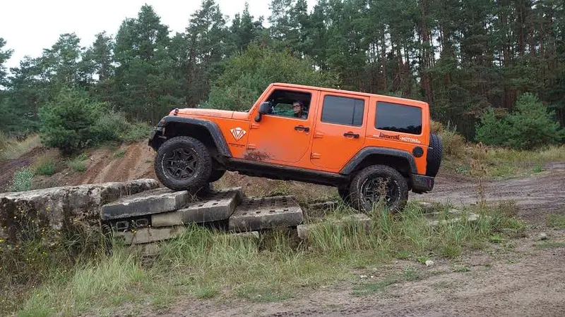 Oranger Jeep Wrangler überquert eine Holzrampe