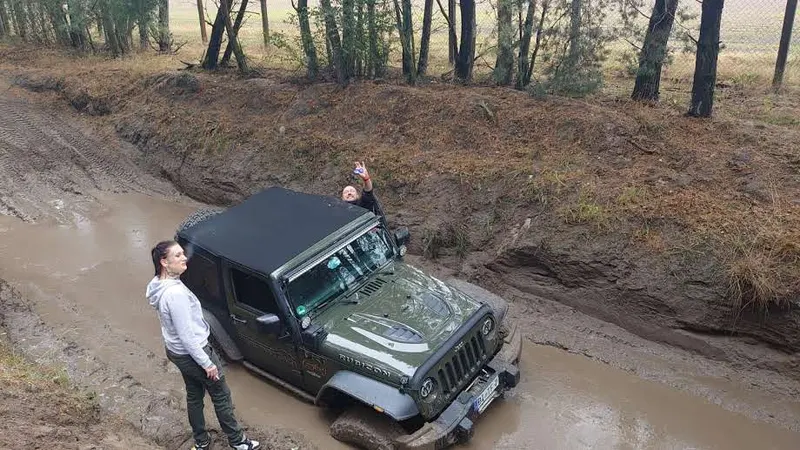Jeep wird aus einem Schlammgraben geborgen, daneben Helfer