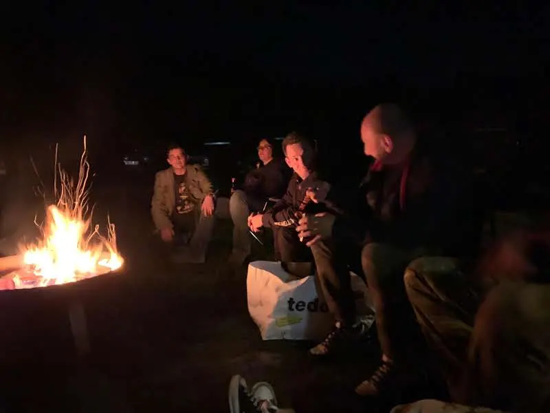 Teilnehmer sitzen abends am Lagerfeuer