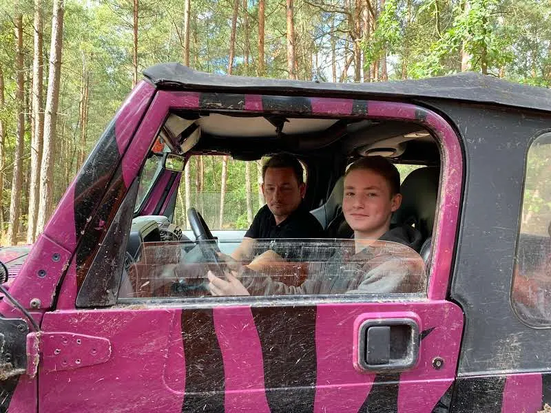 Zwei Insassen in einem pinken Jeep mit Tarnmuster