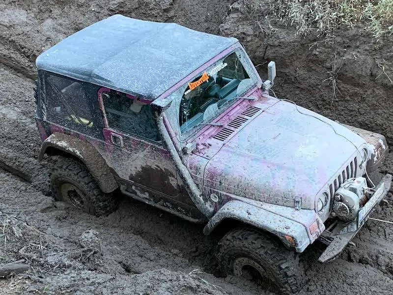 Schlammbedeckter Jeep mit Softtop in einer tiefen Spur
