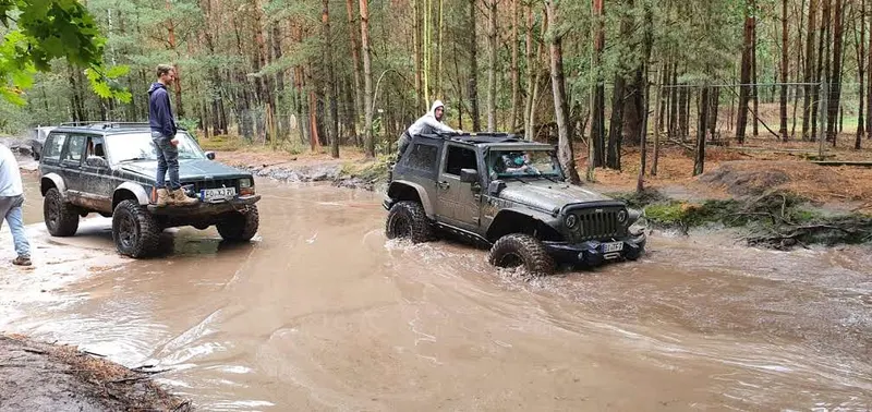 Zwei Jeeps durchqueren eine große Wasserstelle im Wald
