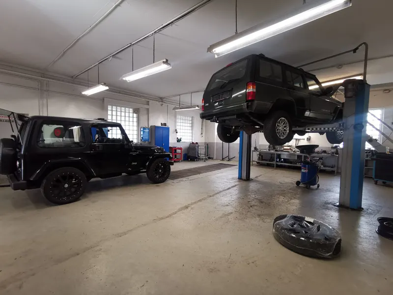 Werkstatthalle mit zwei Jeeps, einer auf der Hebebühne