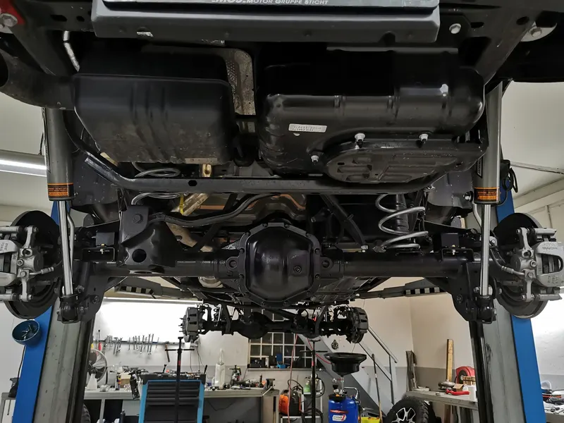 Blick von unten auf einen Jeep auf der Hebebühne: Hinterachse mit Differential, Federn und Stoßdämpfern