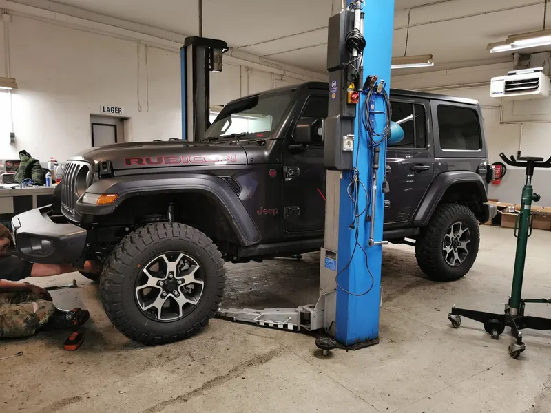 Grauer Jeep Wrangler Rubicon auf der Hebebühne in der Werkstatt