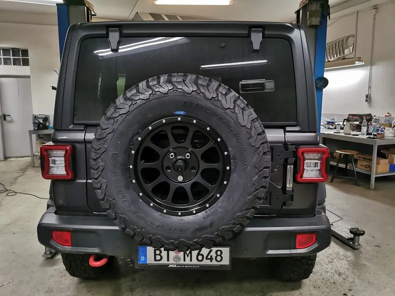 Heck eines grauen Jeep Wrangler mit Reserverad auf neuen Felgen