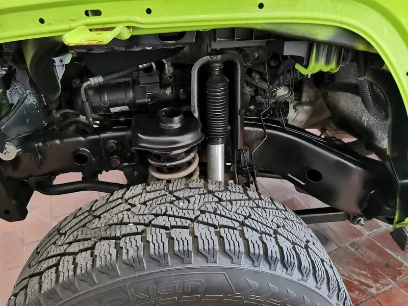 Vorderradaufhängung eines grünen Jeep Wrangler bei abgebautem Kotflügel