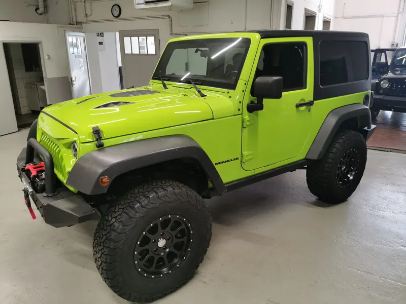 Hellgrüner Jeep Wrangler Rubicon mit schwarzem Hardtop in der Werkstatt