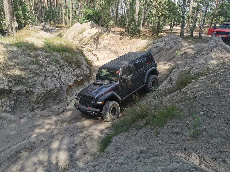 Schwarzer Jeep Wrangler fährt eine steile Sandrinne hinunter