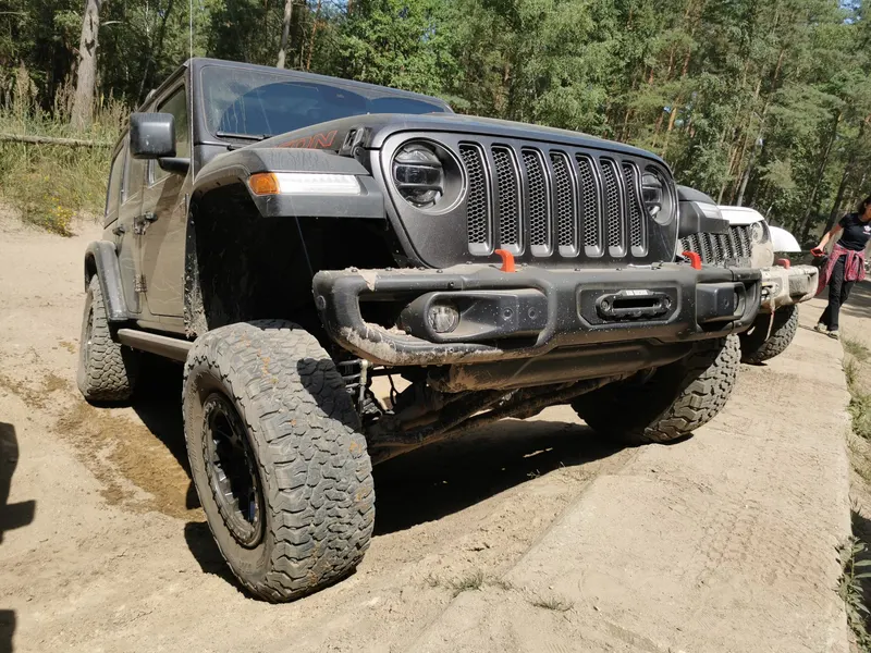 Schwarzer Jeep Wrangler mit Stahlstoßstange auf sandigem Boden