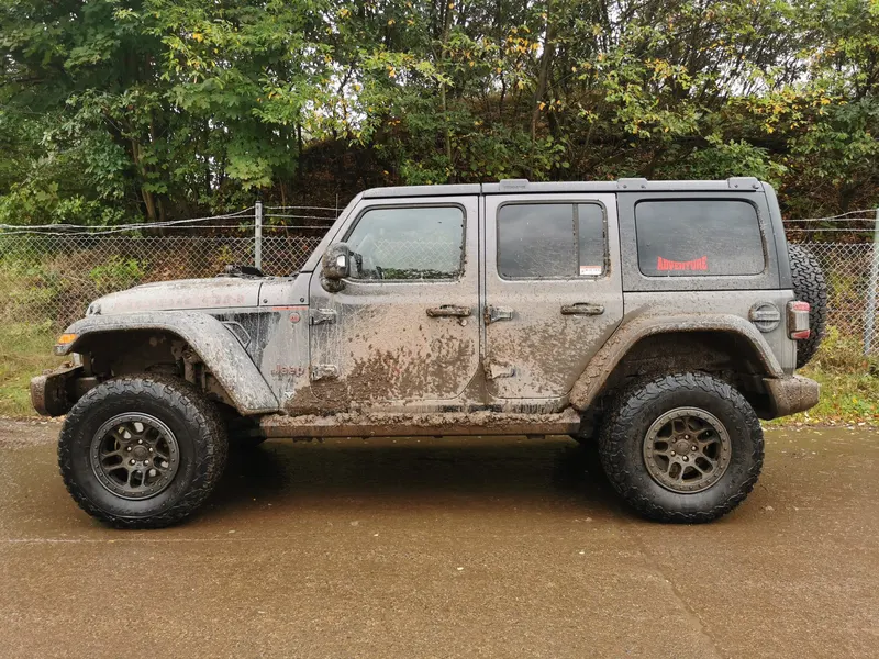 Grauer Jeep Wrangler mit Schlammspuren in der Seitenansicht