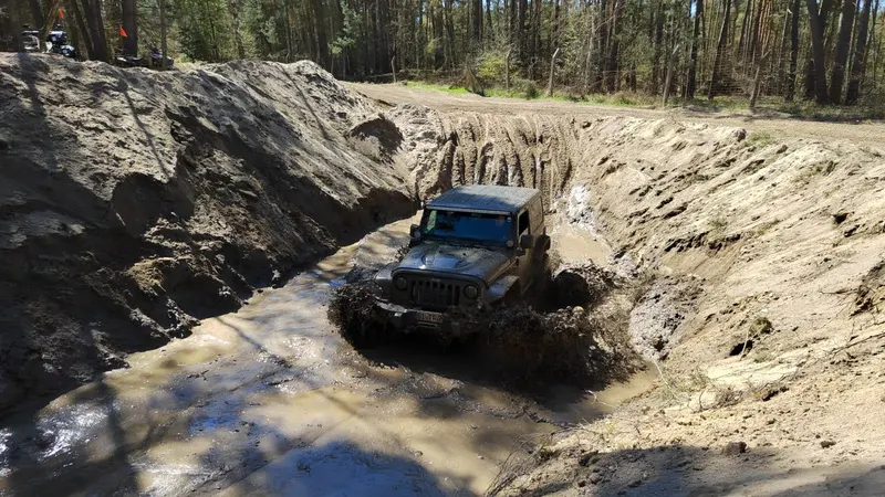 Jeep fährt durch einen tiefen Graben mit Wasser