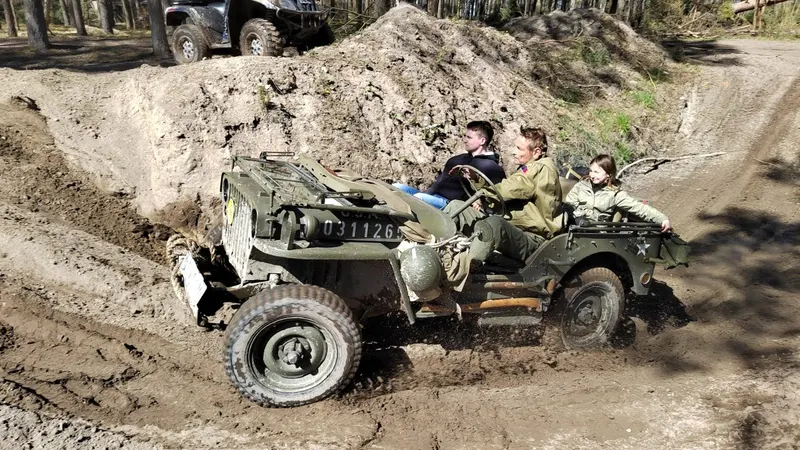 Historischer Willys-Jeep mit Insassen im Sandgelände