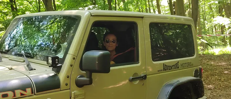 Olivgrüner Jeep Wrangler im Wald, Fahrerin am Fenster