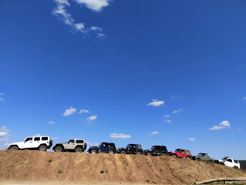 Lange Reihe von Jeeps auf einem Erdwall unter blauem Himmel