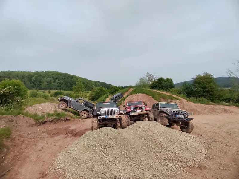 Mehrere Jeeps auf einem Erdhügel im Offroad-Gelände