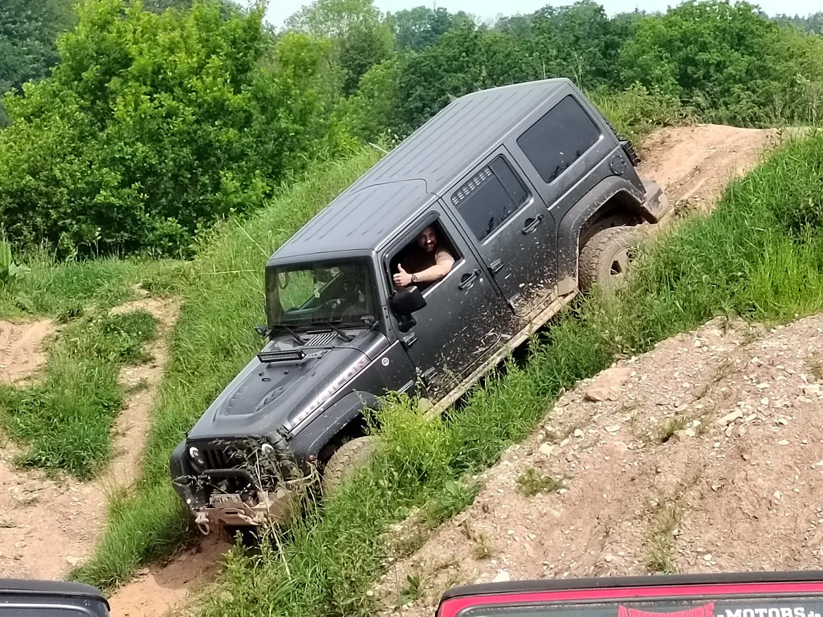 Grauer Jeep Wrangler in starker Schräglage an einem steilen Hang