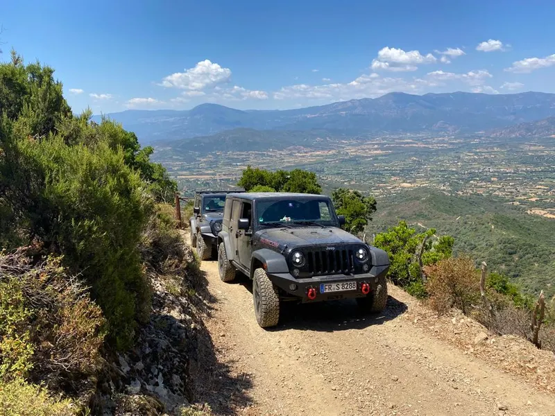 Jeep auf einem Bergweg mit Blick über ein weites Tal