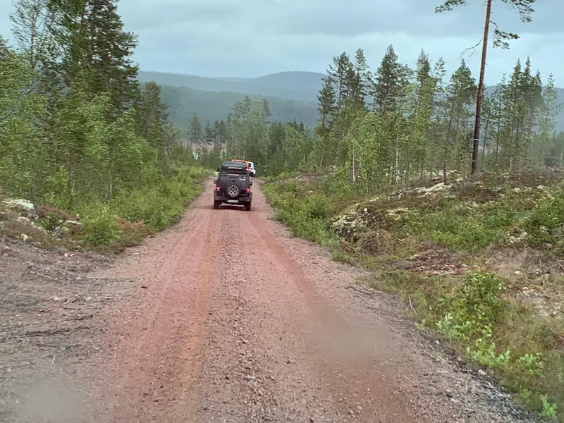 Jeep auf einer roten Schotterpiste durch einen Bergwald