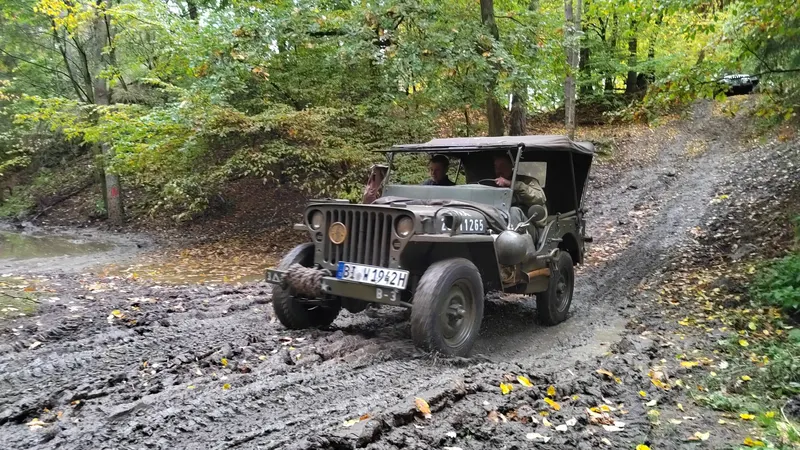 Historischer Willys-Jeep auf einem schlammigen Waldweg
