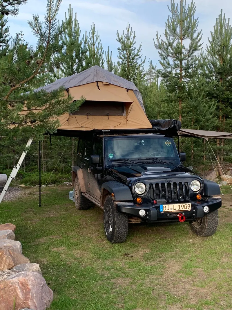 Jeep Wrangler mit Dachzelt auf einem Stellplatz im Wald